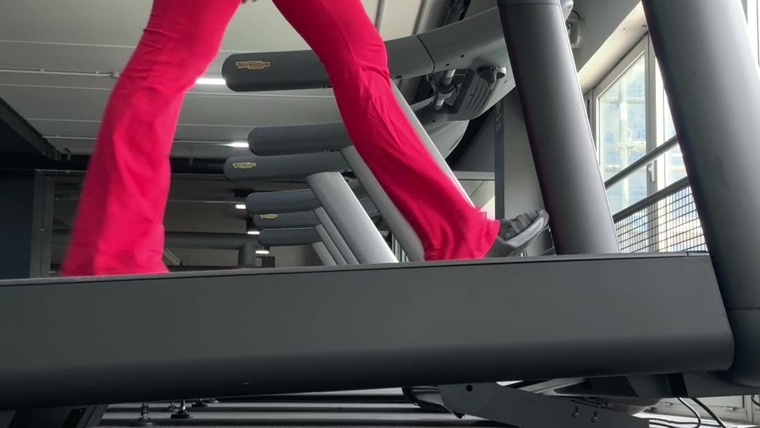 Legs mid stride on a treadmill, seen from the side.